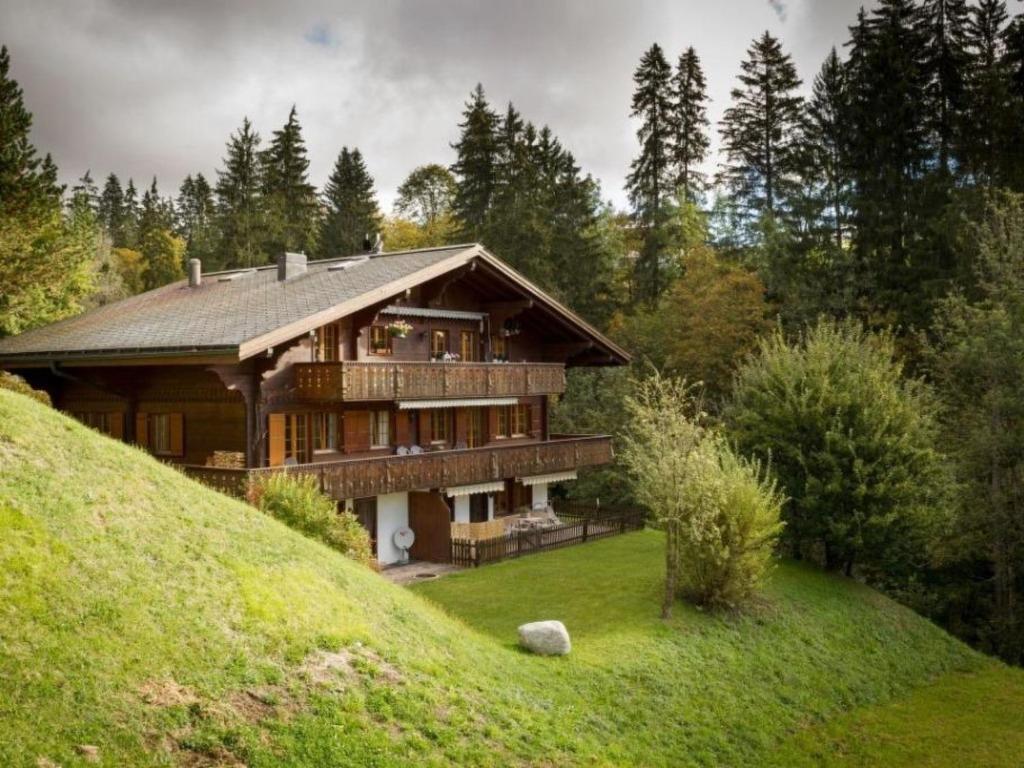 ein großes Holzhaus auf einem Hügel mit Bäumen in der Unterkunft Apartment Graebi by Interhome in Gstaad