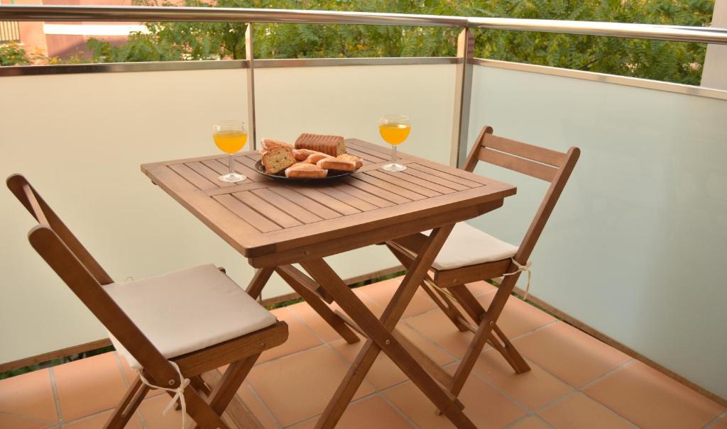 una mesa con 2 vasos de zumo de naranja y pan en el balcón en Apartamentos Navas en Barcelona