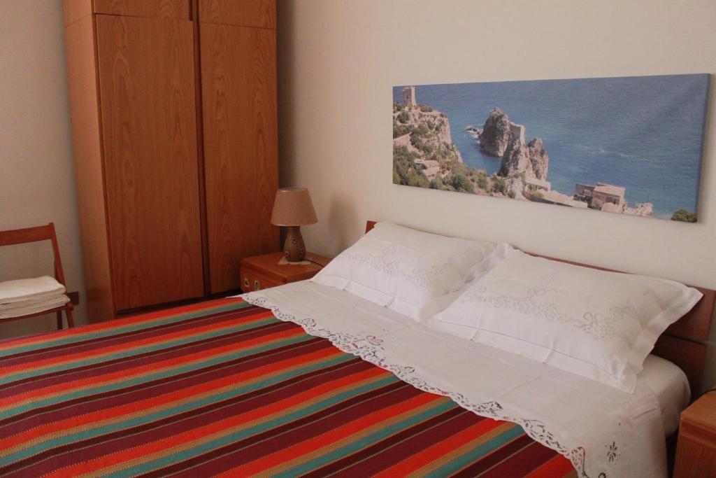 1 dormitorio con 1 cama y una pintura en la pared en Baglio Gammicchia B&B, en Erice