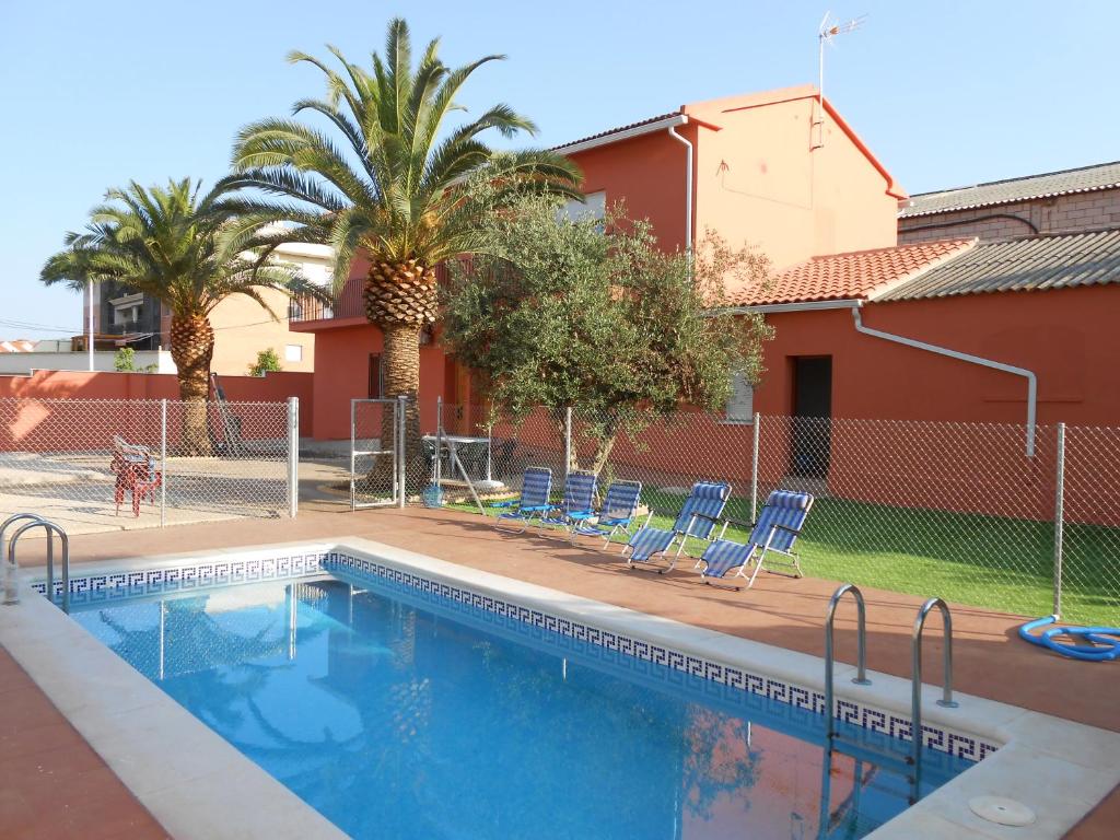 una piscina con sillas azules y palmeras en Apartamentos Turísticos Domus Aquae, en Mérida