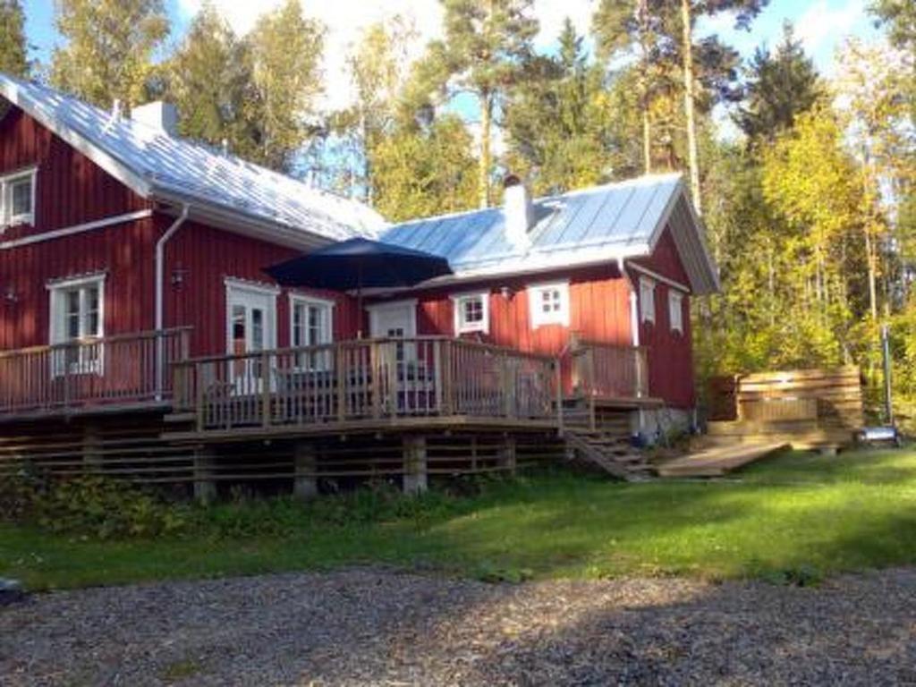 a red house with a porch and an umbrella at Holiday Home Karri by Interhome in Tallnäs