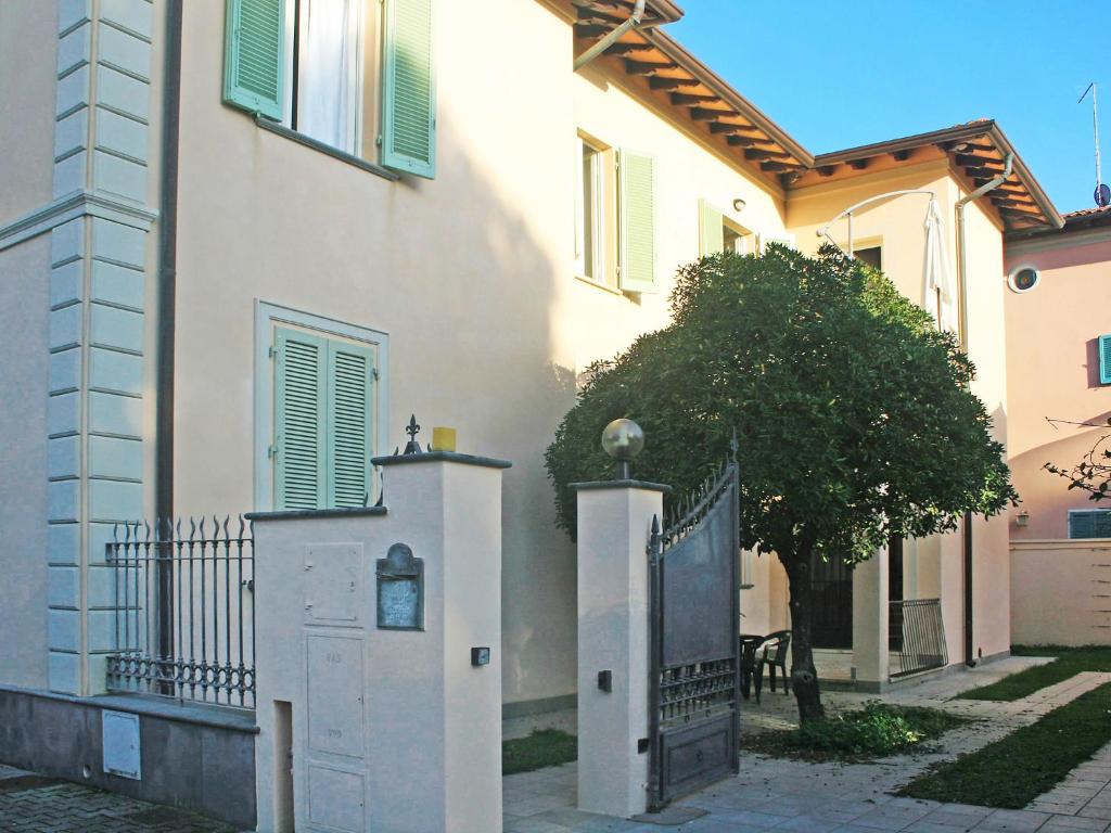 uma casa branca com um portão e uma árvore ao lado em Apartment Milano by Interhome em Forte dei Marmi