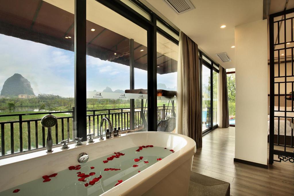 una vasca da bagno in una stanza con una grande finestra di Peach Blossom Resort Hotel a Guilin