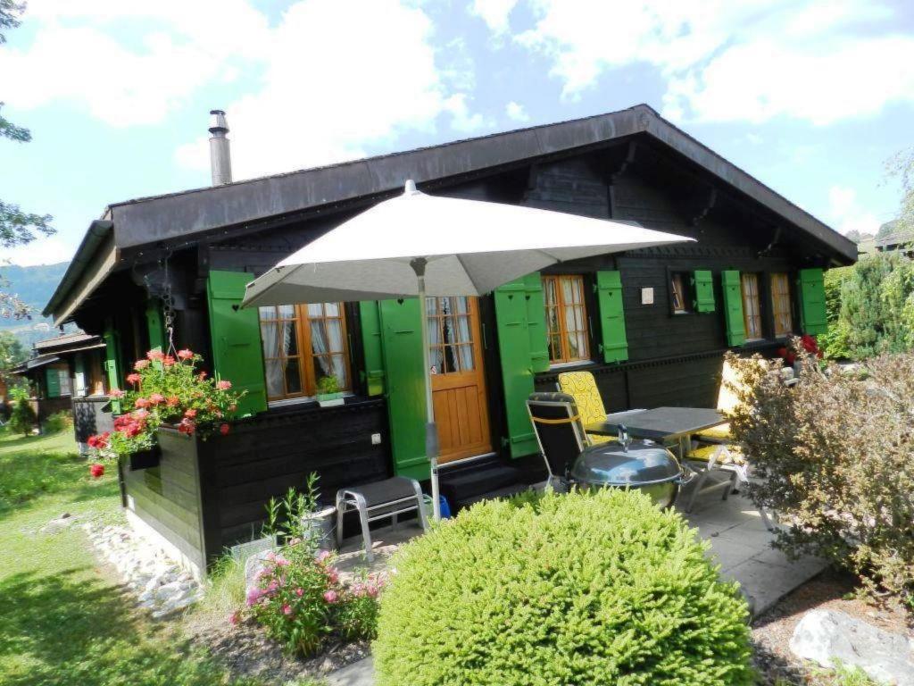 een klein groen huis met een tafel en een paraplu bij Apartment Abnaki- Chalet by Interhome in Gstaad