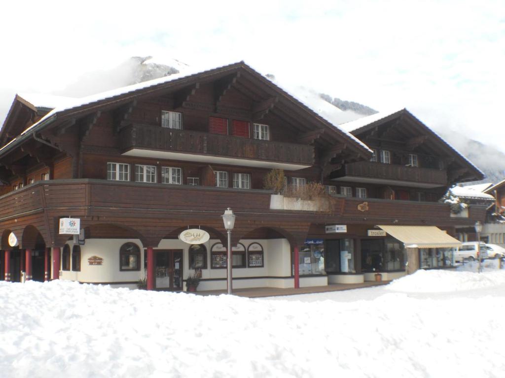 a large wooden building with snow in front of it at Apartment Kronenplatz 7 # 3 by Interhome in Lenk