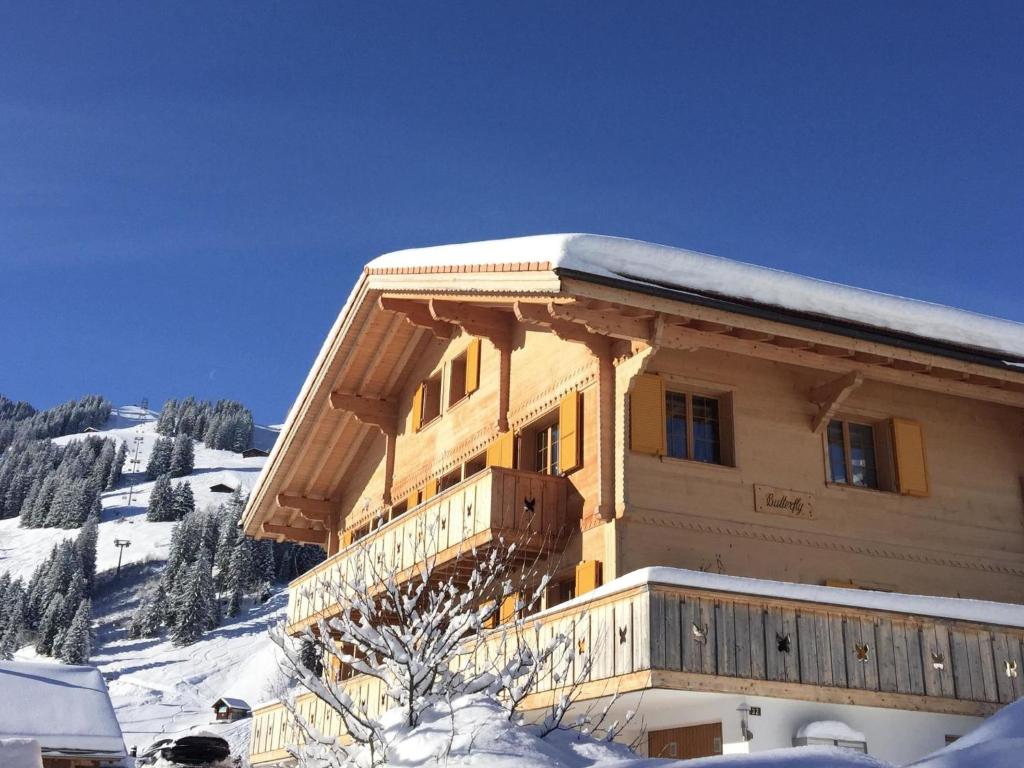 d'un grand bâtiment en bois recouvert de neige. dans l'établissement Apartment Butterfly by Interhome, à Adelboden