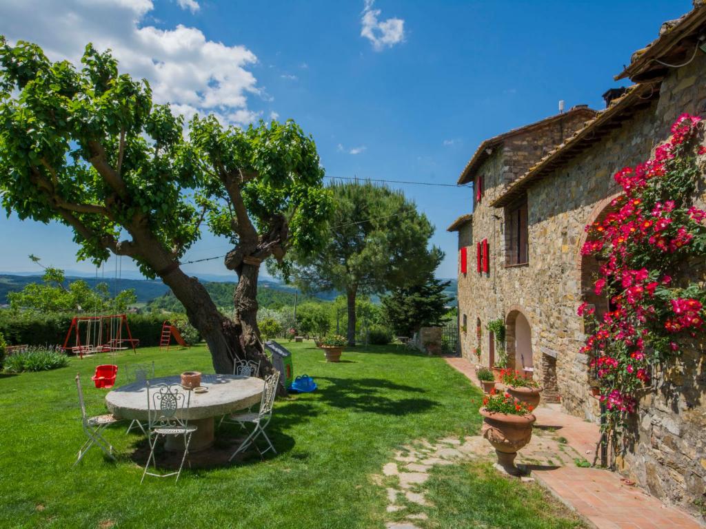 einen Garten mit einem Tisch, einem Baum und einem Gebäude in der Unterkunft Apartment Badia a Passignano-3 by Interhome in Badia A Passignano