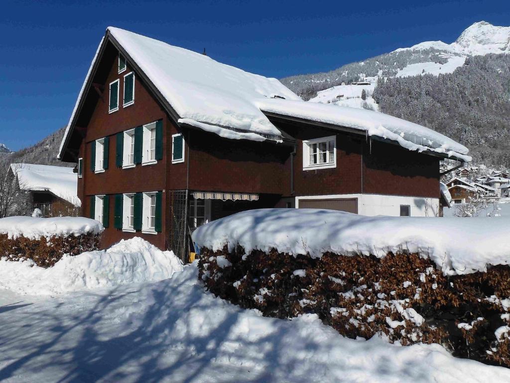 une maison recouverte de neige devant une montagne dans l'établissement Apartment Hälmehois by Interhome, à Gerschnialp