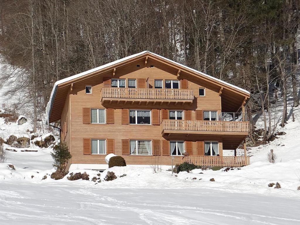 a large wooden house with a balcony in the snow at Apartment Berg by Interhome in Engelberg