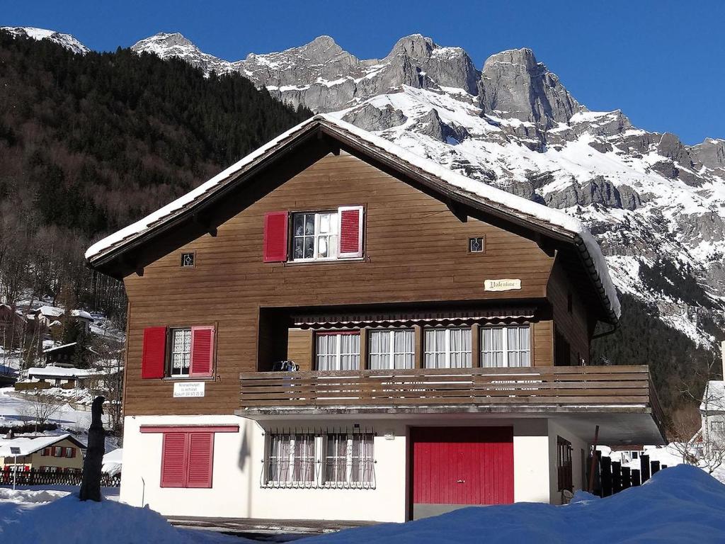 ein Haus mit roten Türen und einem schneebedeckten Berg in der Unterkunft Apartment Valentine by Interhome in Engelberg