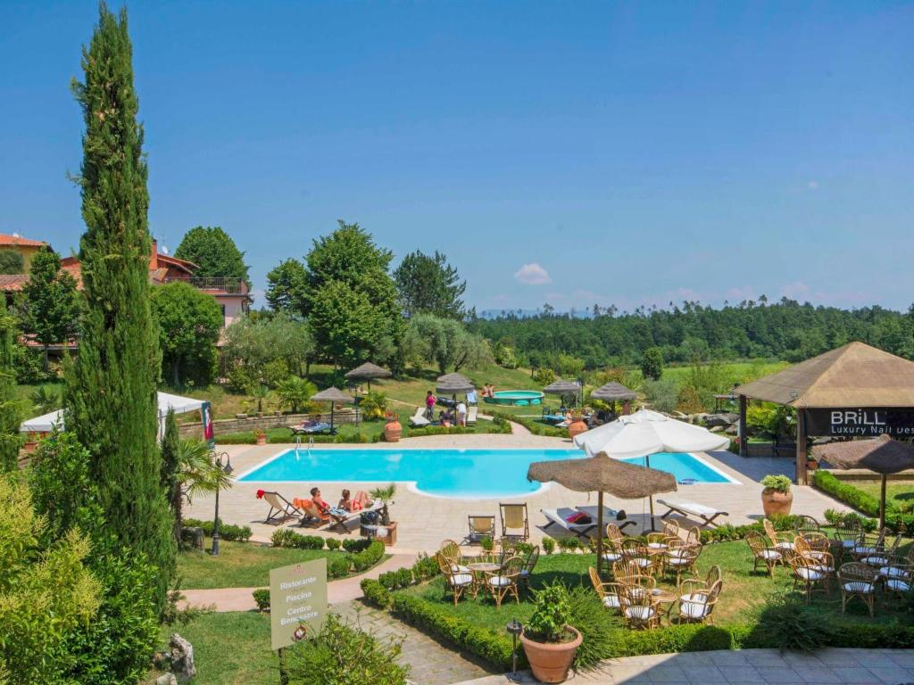 vista sulla piscina di un resort con tavoli e ombrelloni di Apartment Tipologia Bilocale by Interhome a Le Vedute