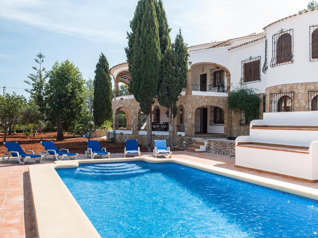 a pool in front of a house with chairs and a house at Apartment Albatros by Interhome in Jávea