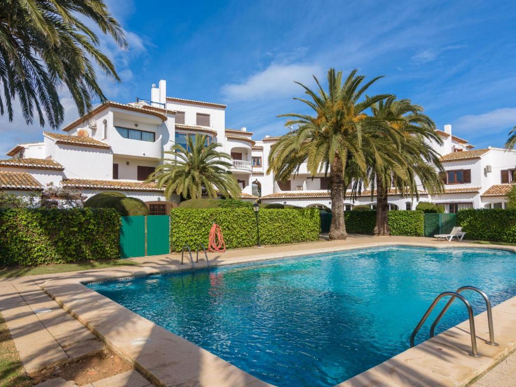 una piscina frente a una casa con palmeras en Apartment Pla by Interhome, en Jávea