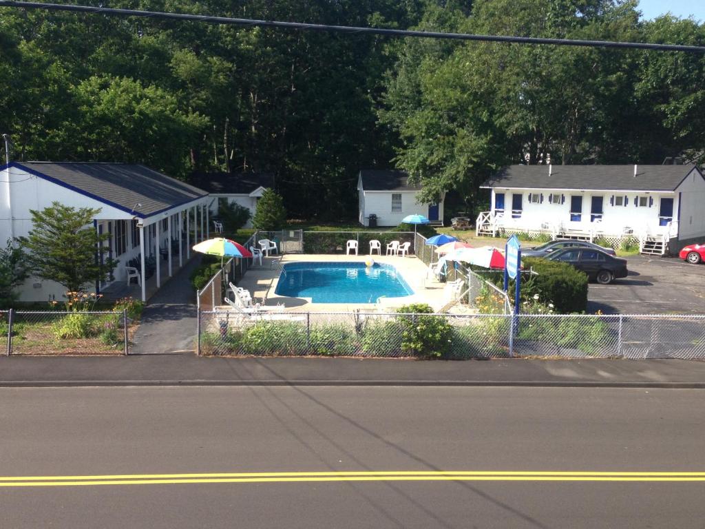 a pool with chairs and umbrellas in a yard at Marvin Gardens Motel Old Orchard Beach in Old Orchard Beach