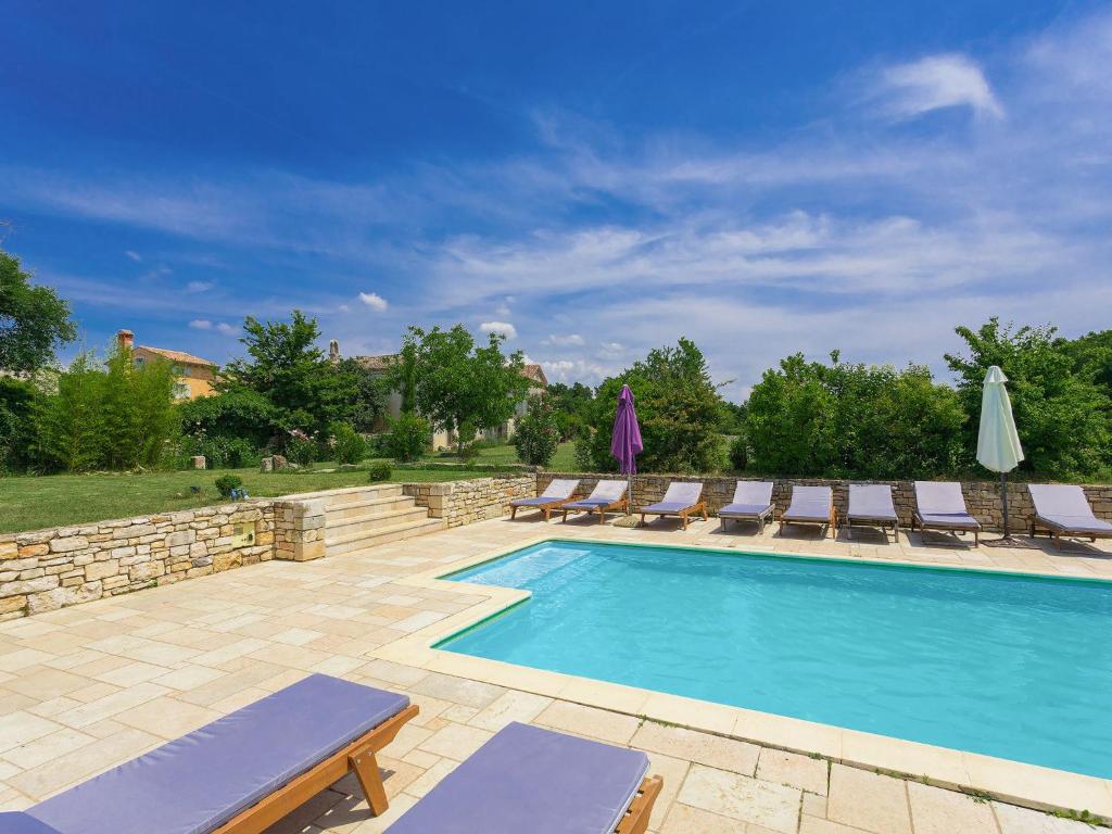 a swimming pool with chaise lounges and lounge chairs at Villa Stancija Negrin by Interhome in Krnjaloža