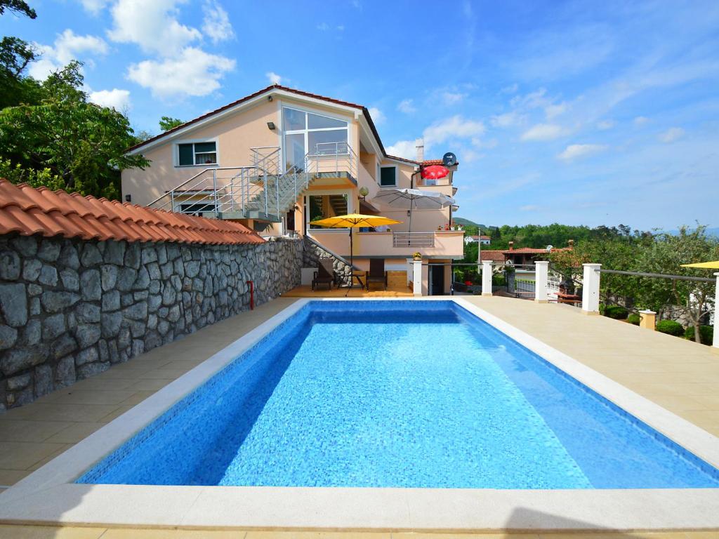 a villa with a swimming pool in front of a house at Apartment Tihomir-1 by Interhome in Veprinac