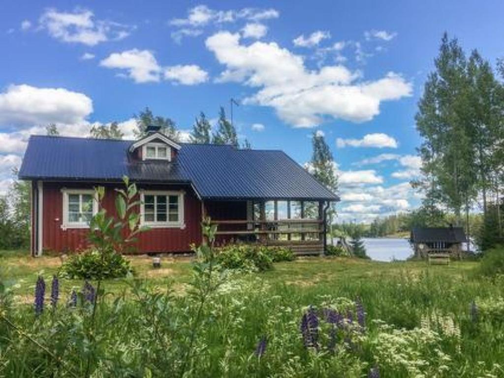 a red house with a black roof in a field at Holiday Home Riihiranta by Interhome in Petäjävesi