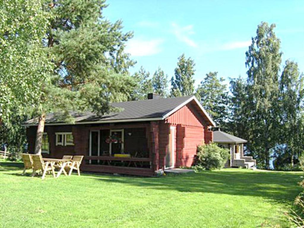 una casa roja con una mesa y sillas en un patio en Holiday Home Rantamökki by Interhome, en Arvaja