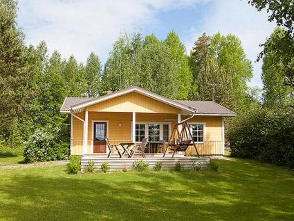 a small yellow house with a porch in a yard at Holiday Home Keltavuokko by Interhome in Sipsiö