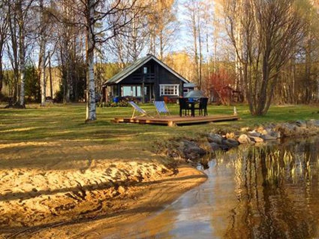 Cabaña con mesa y sillas junto a un río en Holiday Home Kivilahti by Interhome, en Iltasmäki