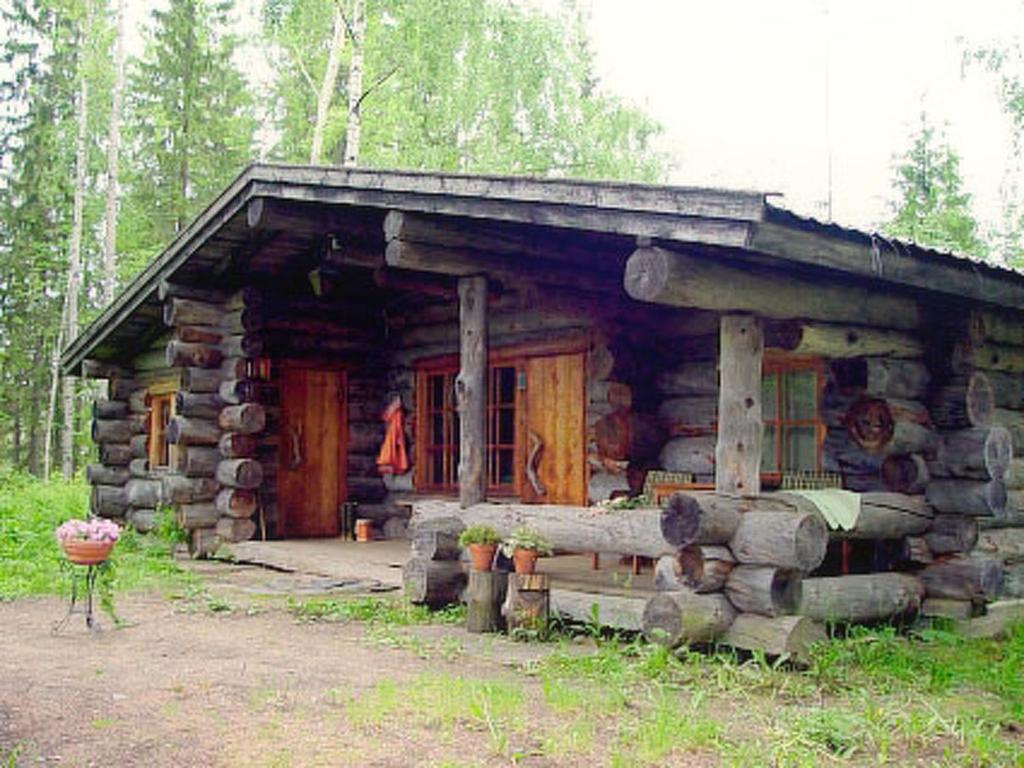 une cabane en rondins dans les bois avec une terrasse couverte dans l'établissement Holiday Home Alppimaja by Interhome, à Pätiälä