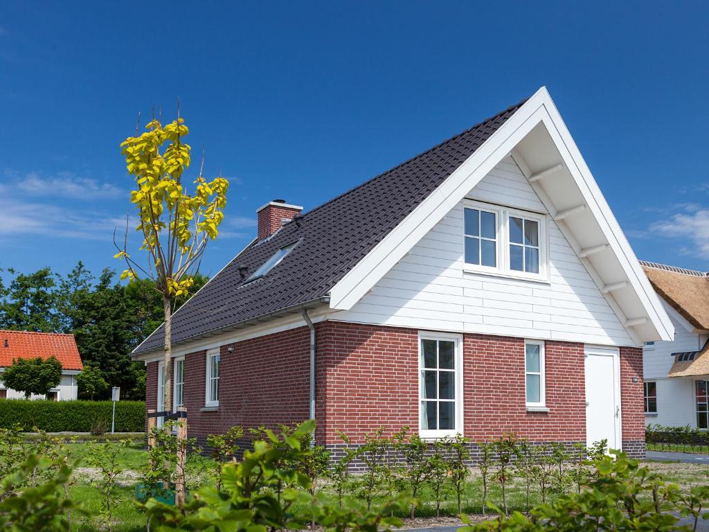 ノールトウェイケルハウトにあるHoliday Home de Witte Raaf-2 by Interhomeの赤レンガ造りの黒屋根