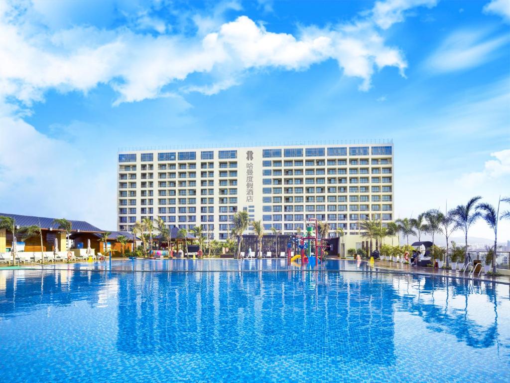 a hotel with a large swimming pool in front of a building at Harman Resort Hotel Sanya in Sanya