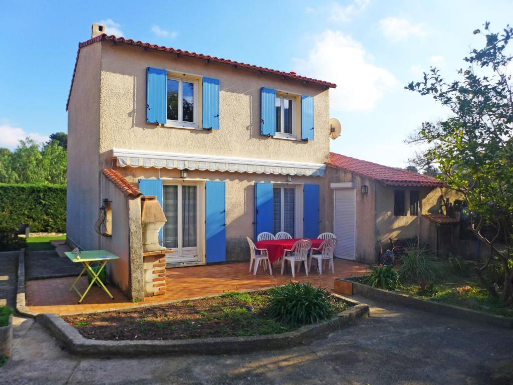 a house with blue shutters and a patio at Holiday Home Les Fées-1 by Interhome in Hyères