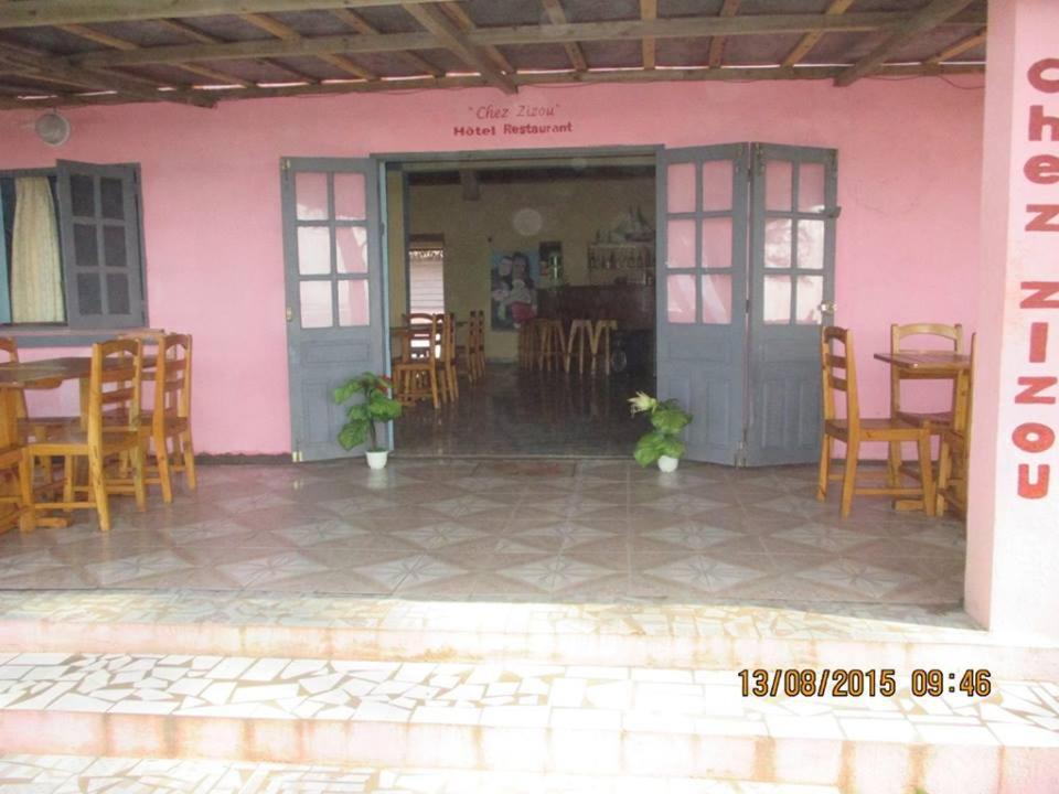 ein rosafarbenes Gebäude mit Stühlen, einem Tisch und einer Tür in der Unterkunft Chez Zizou Manakara in Manakara