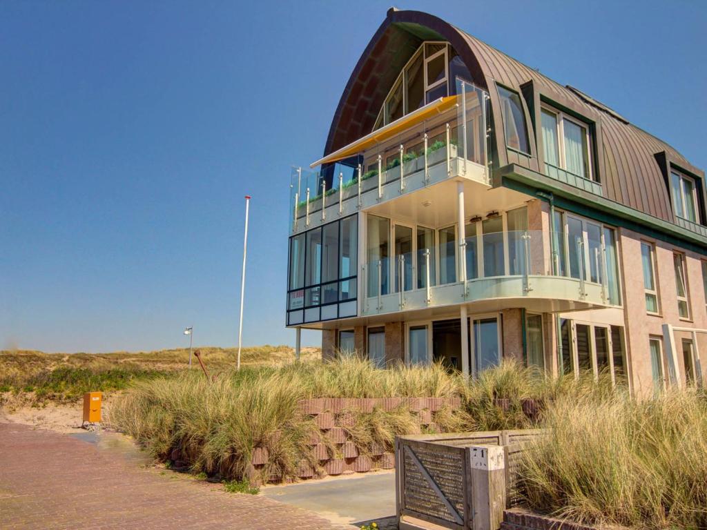 a large building with glass windows on the beach at Apartment De Zeeparel by Interhome in Egmond aan Zee