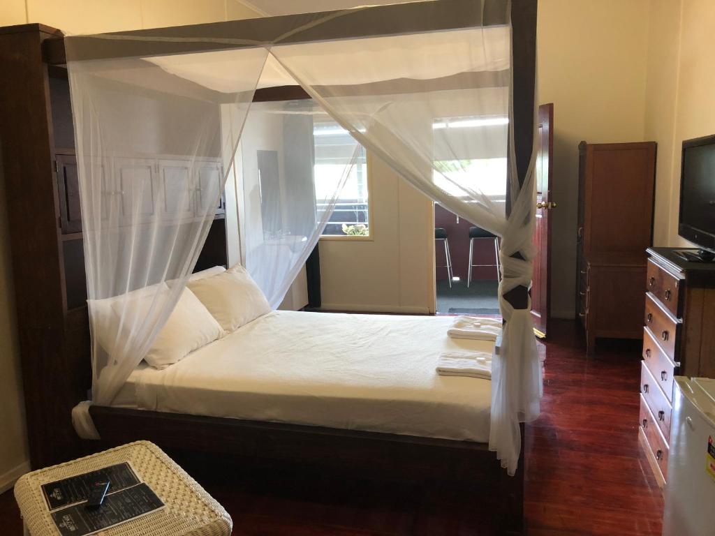 a bedroom with a canopy bed and a television at The Prince of Wales in Proserpine