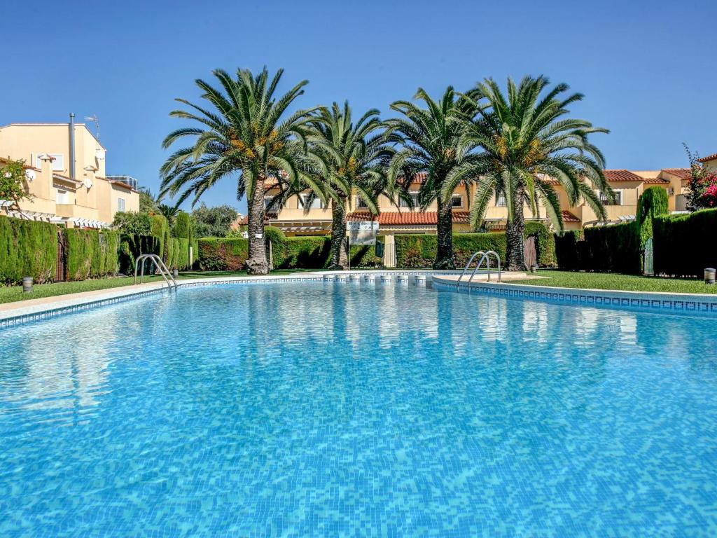 a large swimming pool with palm trees in the background at Apartment El Datiler by Interhome in Denia