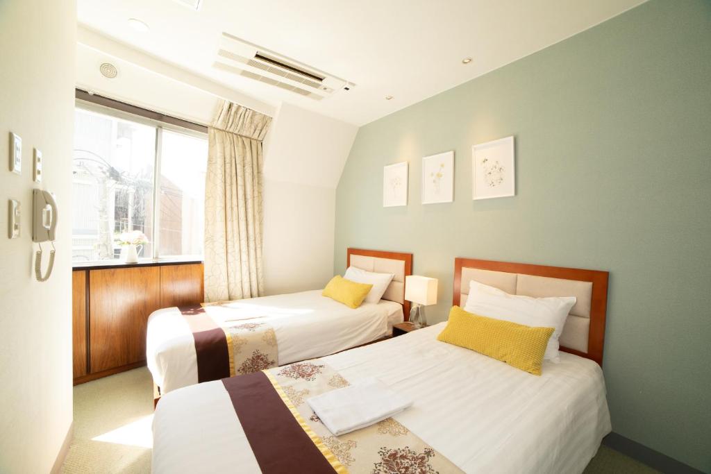 een slaapkamer met 2 bedden en een raam bij Tabata Oji Hotel in Tokyo