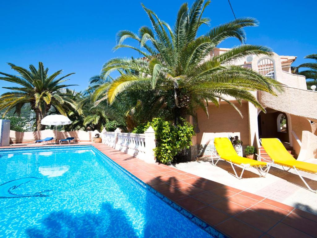 a villa with a swimming pool and palm trees at Apartment Ondina 01 in La Canuta