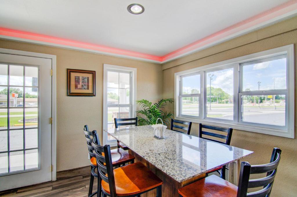 a dining room with a table and chairs and windows at Westbridge Inn & Suites in Clinton
