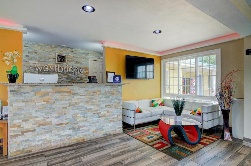 a living room with a couch and a stone wall at Westbridge Inn & Suites in Clinton