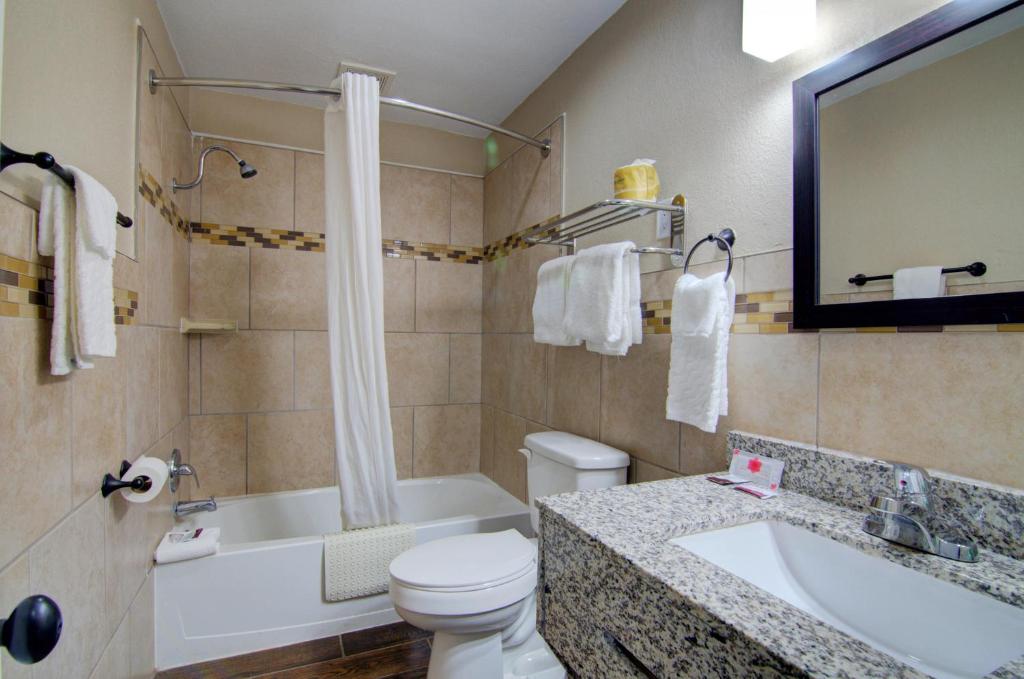 a bathroom with a toilet and a sink and a tub at Westbridge Inn & Suites in Clinton