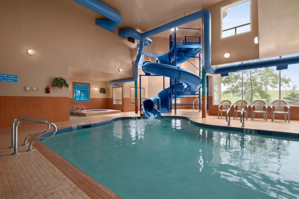 a swimming pool with a slide in a building at Days Inn by Wyndham Red Deer in Red Deer