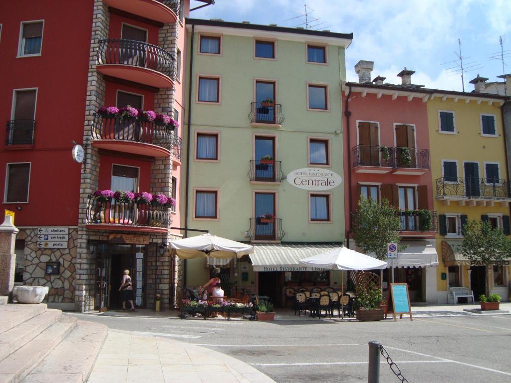 eine Gruppe von Gebäuden mit Tischen und Sonnenschirmen auf einer Straße in der Unterkunft Hotel Ristorante Centrale in Rovere Veronese