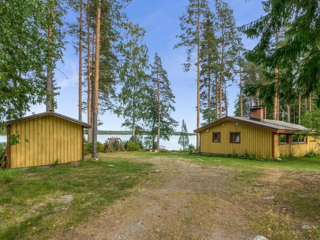 two small buildings in a field with trees at Holiday Home Rantapirtti by Interhome in Niskamäki