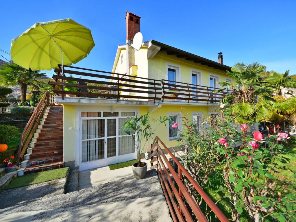 a yellow house with an umbrella and some plants at Apartment Karlo by Interhome in Rukavac