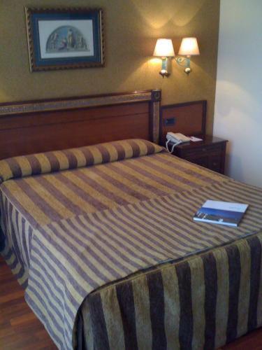 a bedroom with a bed with a book on it at Hotel Begoña Park in Gijón