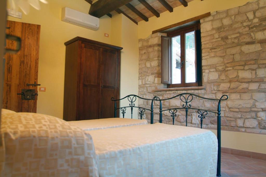 sypialnia z łóżkiem i kamienną ścianą w obiekcie Agriturismo Il Casale w mieście Pergola