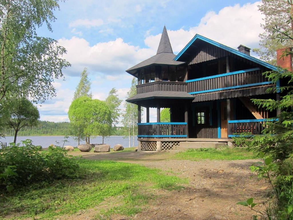 a house with a turret on the side of a lake at Holiday Home Kiviniemi by Interhome in Tohmajärvi