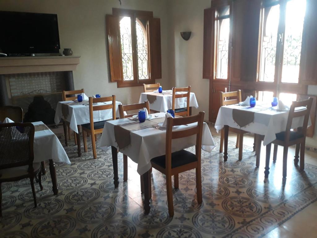 a dining room with tables and chairs and a fireplace at Hôtel Riad Airport Marrakech in Marrakech
