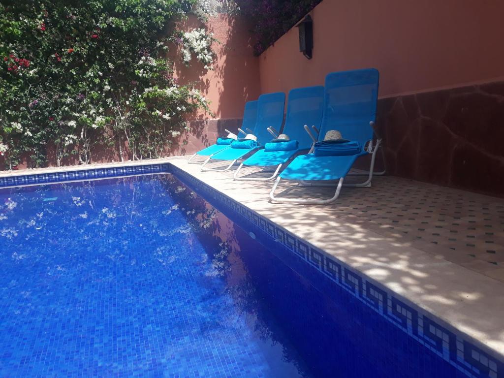 a group of blue chairs sitting next to a swimming pool at Hôtel Riad Airport Marrakech in Marrakech