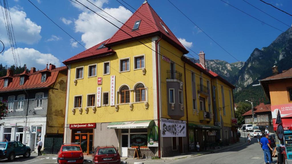 un bâtiment jaune avec un toit rouge dans une rue dans l'établissement Hotel Marasesti, à Buşteni