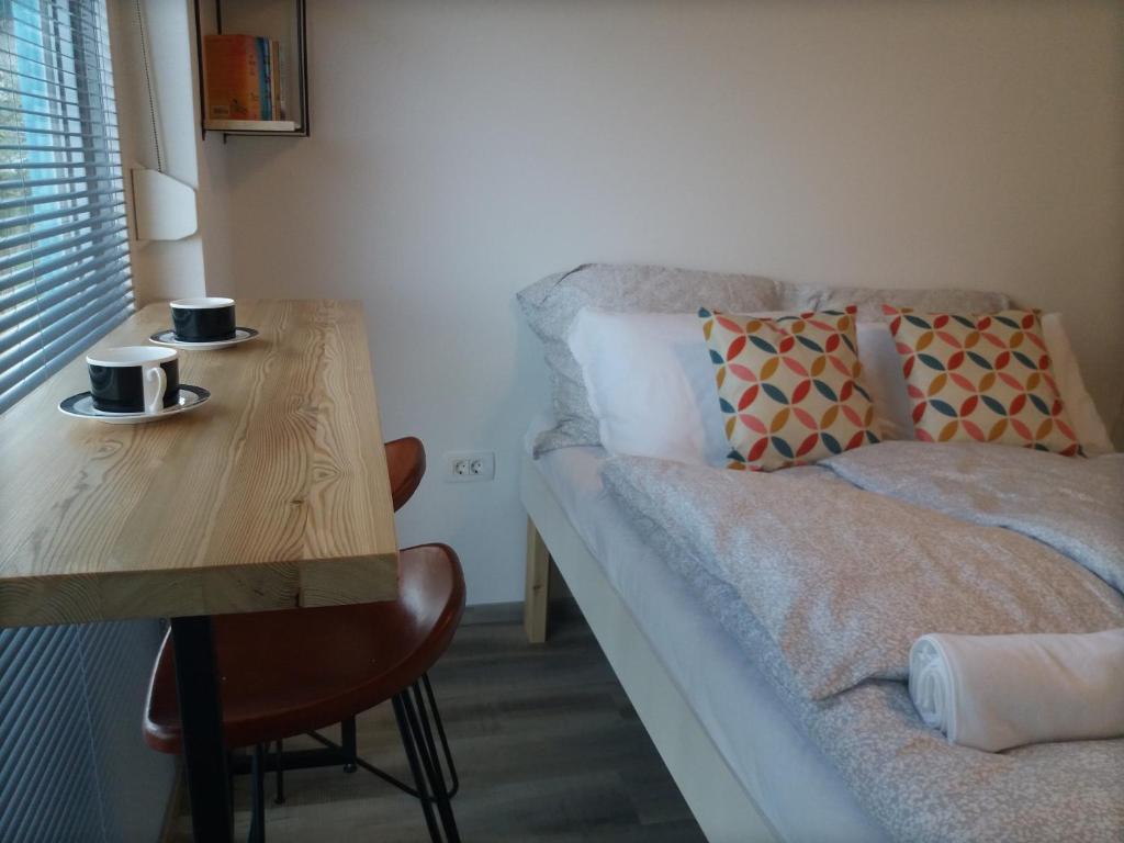 Habitación con cama y mesa de madera con 2 tazas de café. en Mamut Stay en Kamnik
