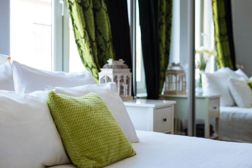 a white bed with a green pillow on it at Angel House Bed & Breakfast in Kraków