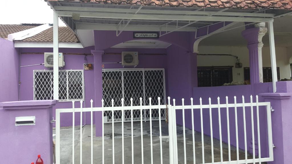 a purple house with a white fence in front of it at Cottage Muslim Homestay ByWawaSha in Tanjung Malim